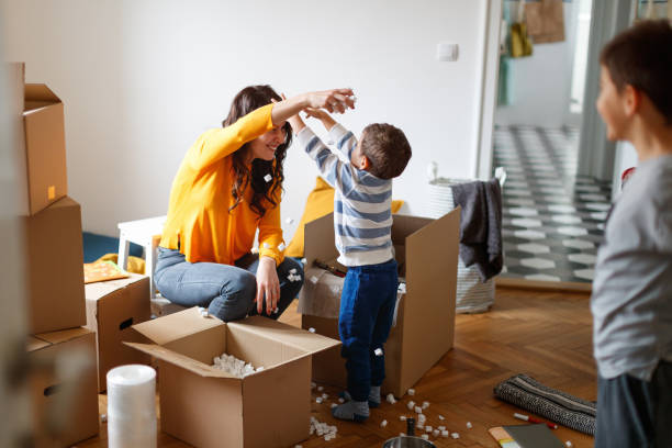 istock Mother playing with toddler, taking packing peanut from boxes and throwing on each other's head 1296452892