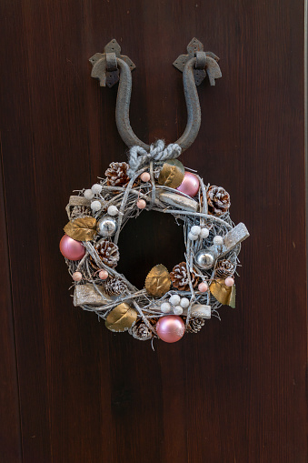 Christmas ornament on the outside of a rustic wooden door hanging from a metal support