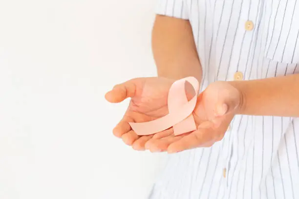 Hand holding Peach color ribbon on white background with copy space, symbol for Uterine and Endometrial cancer awareness, World Cancer Day. Healthcare or hospital and insurance concept.