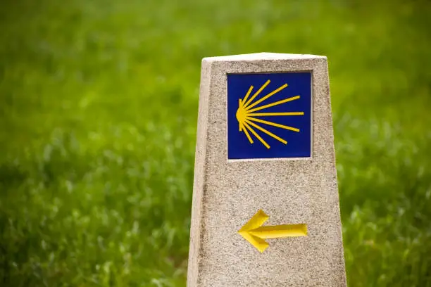 Camino de Santigo milestone, information sign as it goes through Lugo province, Galicia, Spain. Scallop pilgrimage symbol and yellow arrow . Copy space on the left.