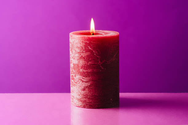 istock Burning red candle on purple background 1296457485