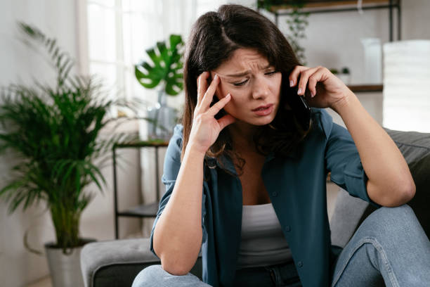 istock Sad woman sitting on the couch, using the phone. 1296457909
