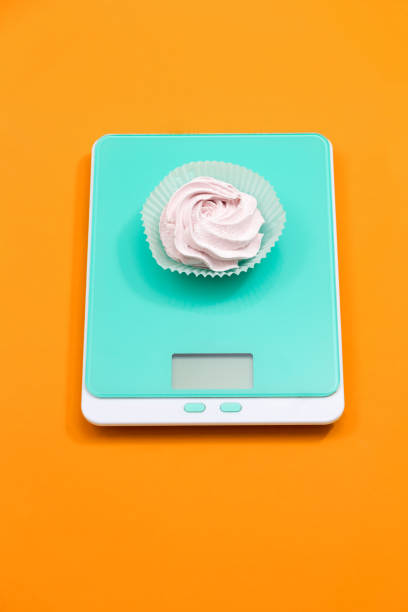 Marshmallow on an electronic scale on an orange background. stock photo