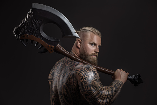Fantasy axe wielding muscled viking warrior in studio shot