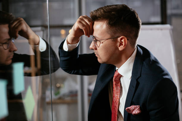 istock Tired businessman in conference room use sticky notes on glass wall. 1296465220