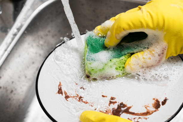 istock Close up hand with a sponge washes a dirty plate under running water 1296466238