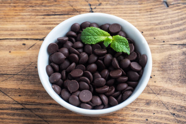 istock Chocolate drops for decorating desserts in a plate with mint on a wooden background. 1296468467