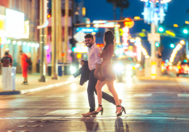 NIght out together in Vegas A young couple enjoying the Las Vegas nightlife together, crossing a bright street surrounded by neon. the strip las vegas stock pictures, royalty-free photos & images