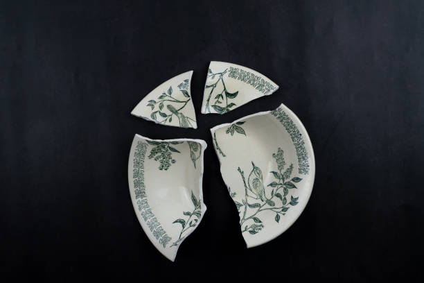 Broken plate on a black background. A deep pictured rarelka shattered into four fragments. Insulated porcelain old tableware