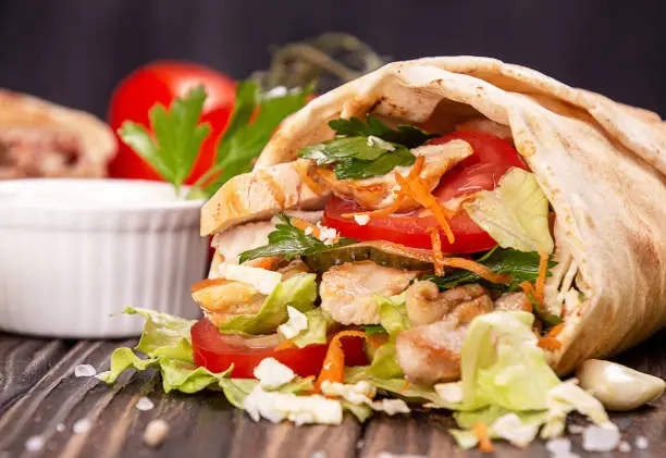 Popular arabic turkish fastfood doner shawarma roll with meat and vegetables and ingredients on wooden background. top view