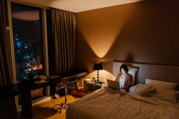 istock Young asian woman working late and using a laptop in bed 1296479043
