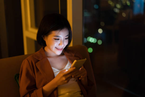 istock Cheerful young woman using smartphone at night 1296479067