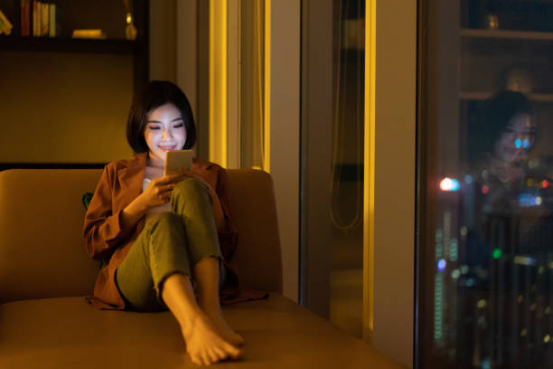 istock Smiling young asian woman using smartphone at night 1296479070