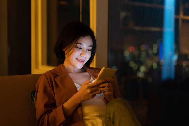 istock Cheerful young woman using smartphone at night 1296479582