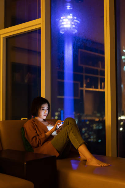 istock Beautiful Asian woman using smartphone at night 1296479592