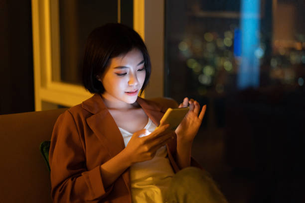 istock Beautiful Asian woman using smartphone at night 1296479602