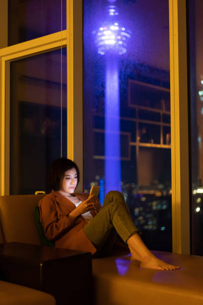 istock Beautiful Asian woman using smartphone at night 1296479608