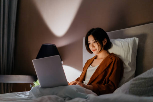 istock Young asian woman working late and using a laptop in bed 1296479628