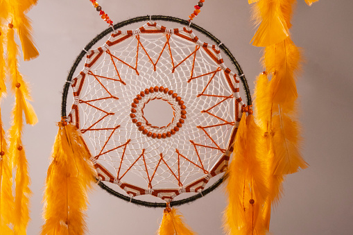 Dreamcatcher made with orange strings drawn on a white background