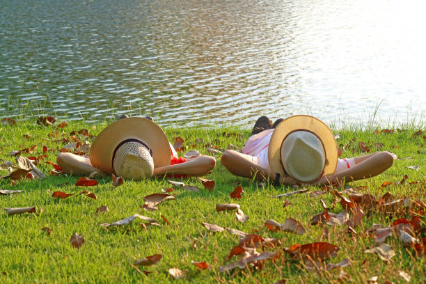 Couple in wide brim hat lying side by side on the sunny waterfront, ( Self Portrait )