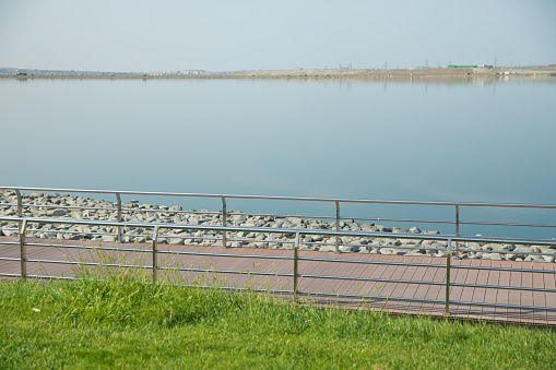 An oval bridge from iron and wood on the edge of the lake . Boyukshor Lake in Baku Azerbaijan . According to geological data, the average depth of the water in the lake is 3.40-3.95 meters .