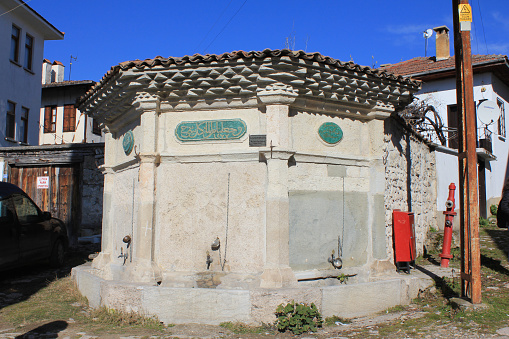 Karabuk, Turkey-February 6, 2011: A fountain with Arabic inscriptions on it, from the Ottoman period, on the street in a sunny day in Yoruk Village. Fresh air, clear sky.