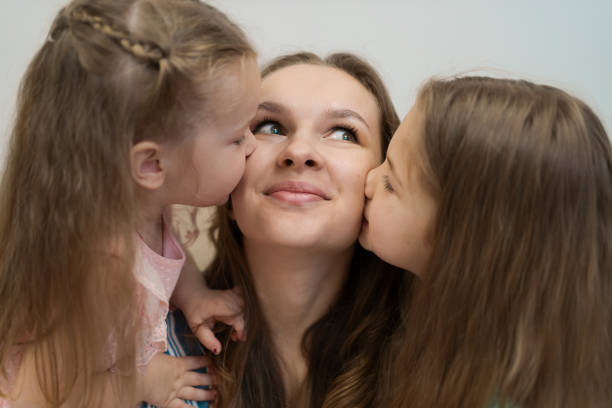 istock Two daughters kissing their mommy 1296486812