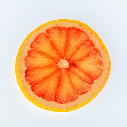 A slice of grapefruit on a white background.
