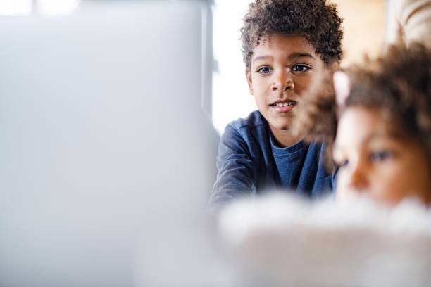 istock Small black kids watching cartoons on a computer at home. 1296488038