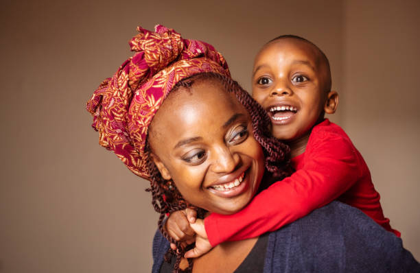 istock Smiling mom carrying her laughing little boy on her back 1296488094