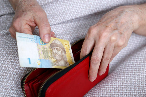 mujer de edad avanzada saca la hryvnia ucraniana de su cartera - ukraine hryvnia currency paper currency fotografías e imágenes de stock