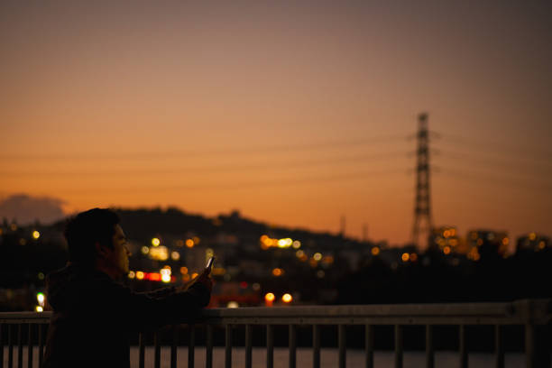 A Japanese man using a charged smartphone.