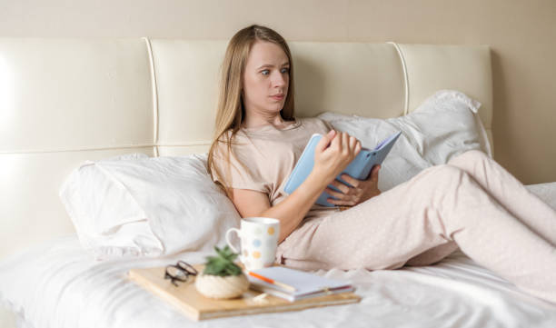 istock Surprised woman in bed reading with notepad 1296493932