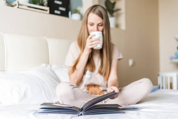istock Blonde woman in bed with book 1296494011