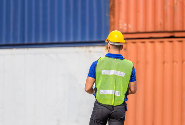 istock Foreman worker in hard hat and safety vest at containers cargo 1296497983