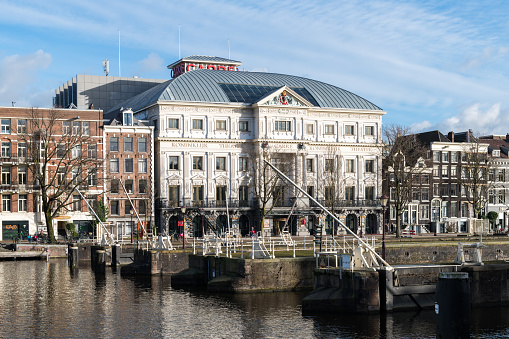 The Royal Theatre Carré at the riverbank of the Amstel River in Amsterdam. In front of the theatre is a complex of traditional sluices.