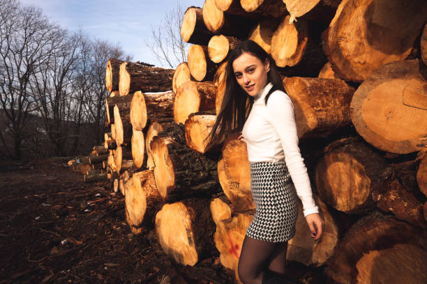 Young woman on a cold day behind cut trunks.