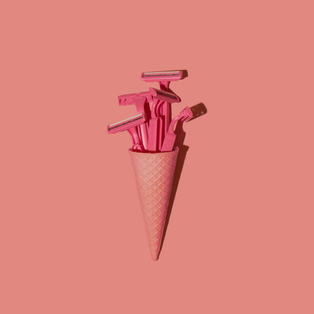 istock Ice cream cone with pink safety razors on pastel pink background. Abstract creative minimal concept. 1296503853