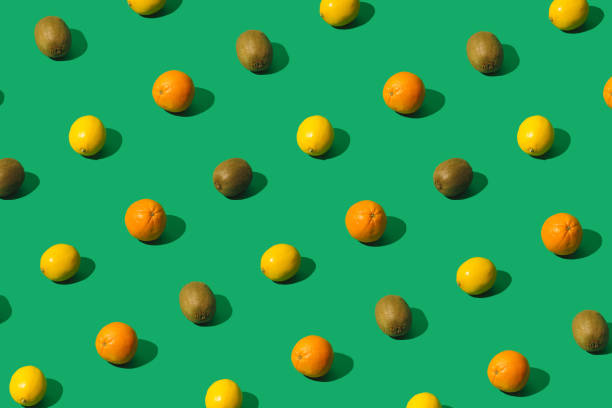 istock Lemons, oranges and kiwis creative pattern on a green background. Minimal sunlit layout. 1296504643