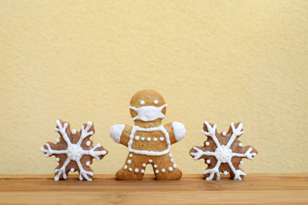 istock Gingerbreads decorated with white icing - man with protective face mask and snowflakes 1296505217