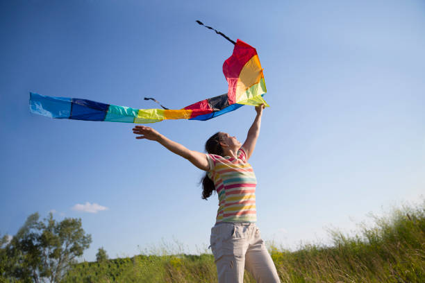 istock woman with a kite in the field 1296505401