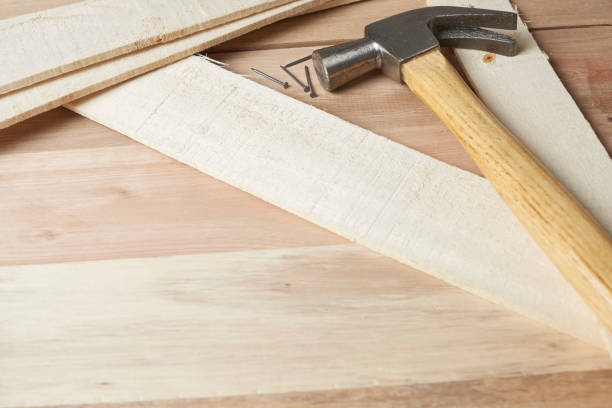 Concept of carpentry. Work table, wooden surface on which there are some wooden strips, some nails and a hammer.