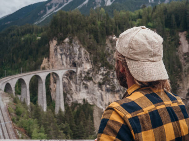 istock Man contemplates railroad track viaduct in Switzerland 1296512921