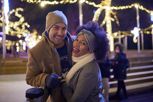 A young couple posing for a photo at ice rink on a beautiful night. Skating, closeness, love, together
