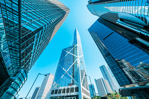 Low angle of modern highrise building with reflection glass in the city wth blue sky