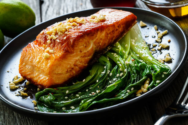istock Fish dish - salmon steak with pak choi cabbage on wooden table 1296514515