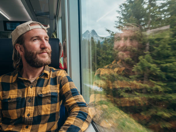 Man traveling by train looking from the window enjoying passing scenery Swiss Alps outside, red train, Switzerland mid adult men stock pictures, royalty-free photos & images