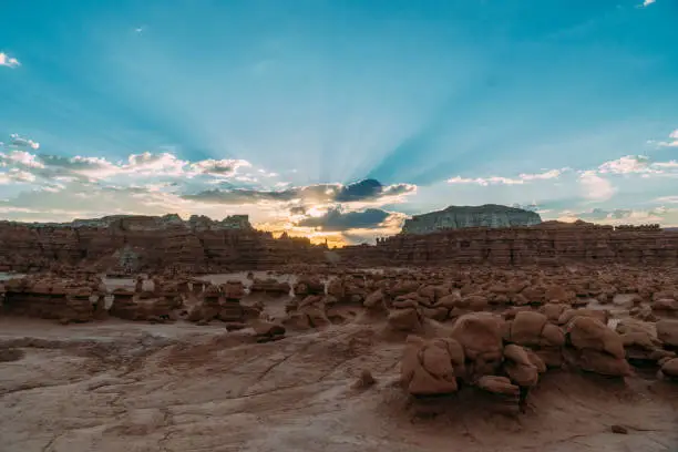 Beautiful sunrise view of goblin valley state park, Utah, with light-rays peaking from behind the large mushroom shaped rocks in the desert.