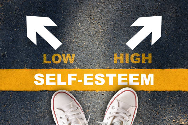 Boosting self esteem concept and improvement idea Self-esteem written on yellow line with low and high with white arrow on asphalt road low self esteem stock pictures, royalty-free photos & images