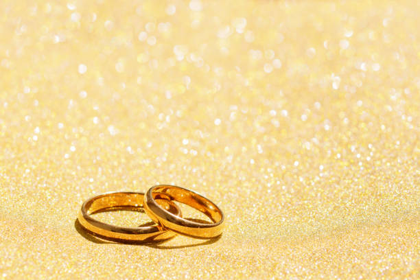 istock Two gold wedding bands on a glitter background. 1296518428